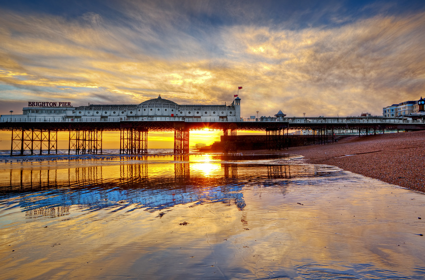 Brighton Pier with a fiery sunset reflected in the sea at the beach