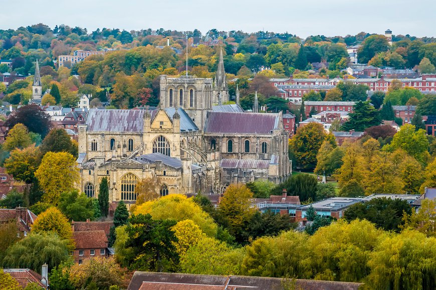 A view from St Giles Hill towards the cathedral, green trees and homes in the city of Winchester, UK in Autumn
