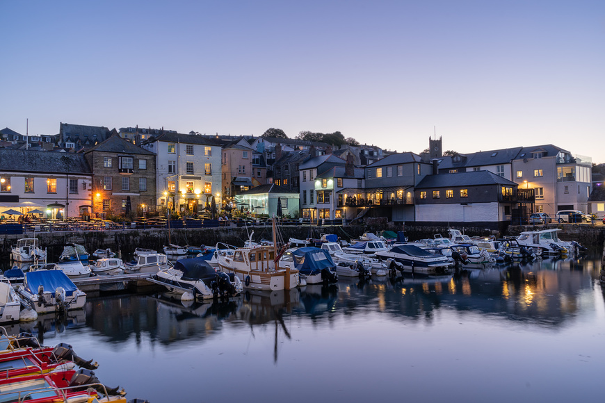 Sunset view of the Custom House Quay, the sea, boats and lit up pubs, restaurants and homes in Falmouth Cornwall England