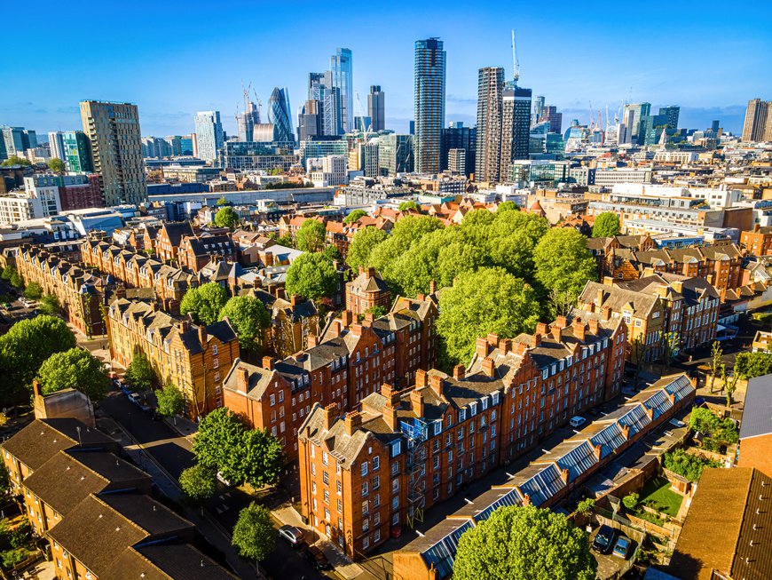 Aerial view of Shoreditch showcasing the diverse landscape with residential properties, trees above the houses and high rise blocks in the background with the Gherkin commercial skyscraper in the distance