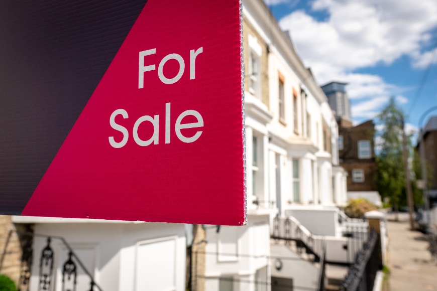 Estate agent 'For Sale' sign on street of houses