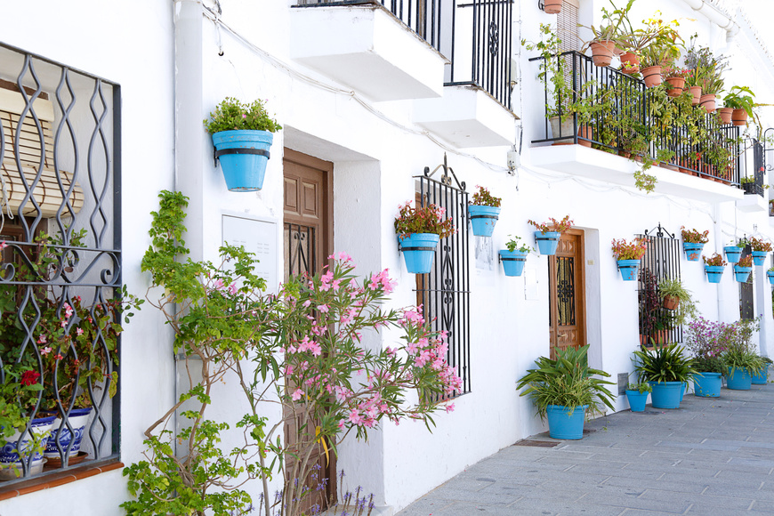 Picturesque street of Mijas with blue flower pots in facades, a traditional whitewashed village, Malaga, pain
